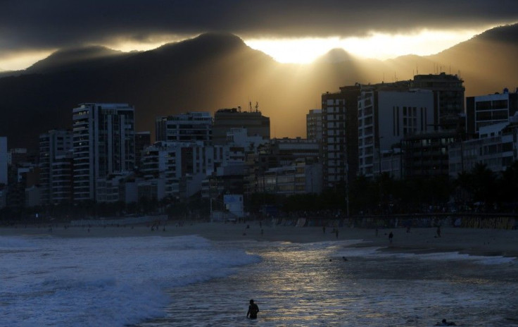 A man wades in the sea at Ipanema Beach during sunset in Rio de Janeiro June 4, 2014. Rio de Janeiro, with its white beaches, blue ocean and jungle-covered mountains, is still the place that comes to mind when people think of Brazil. Soccer fans coming to