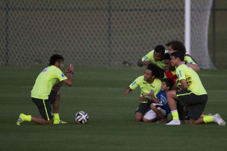 Brazil&#039;s Neymar takes photos for a fan and his teammates on the pitch after a training session in Teresopolis near Rio de Janeiro