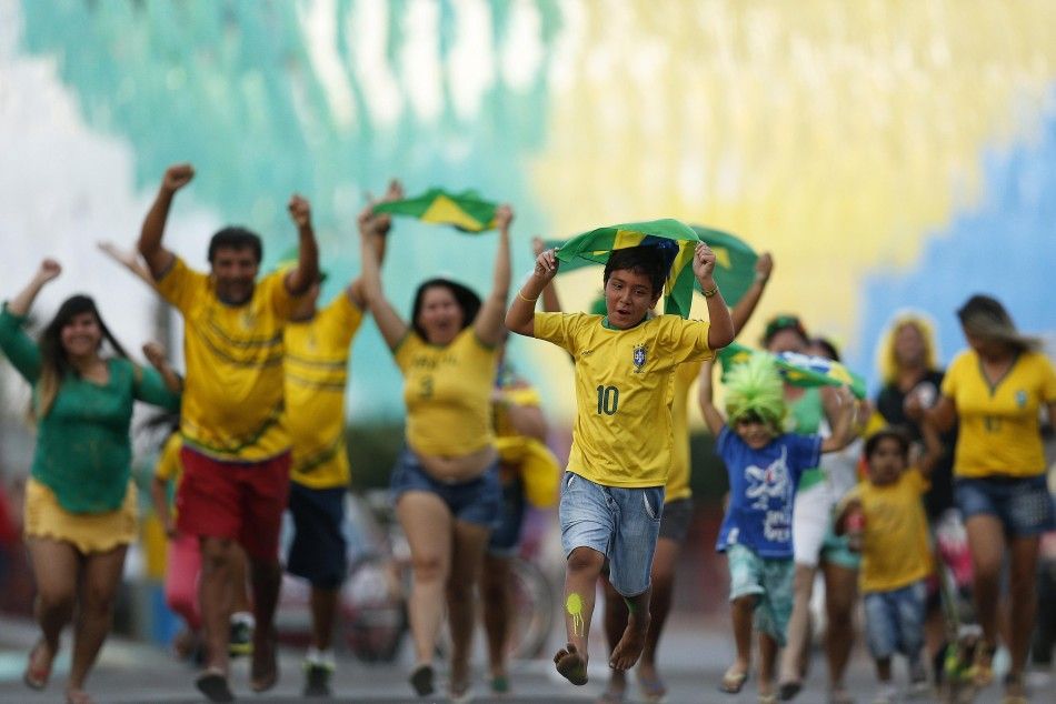 Residents run to celebrate after decorating a street in the colours of Brazils national flag