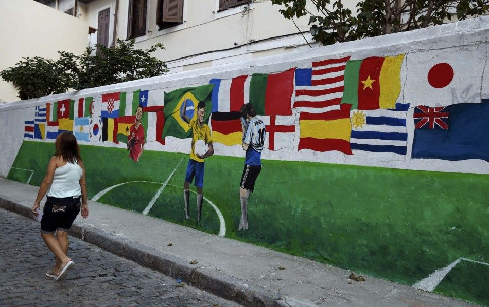 A woman walks past a mural showing flags of various nations 