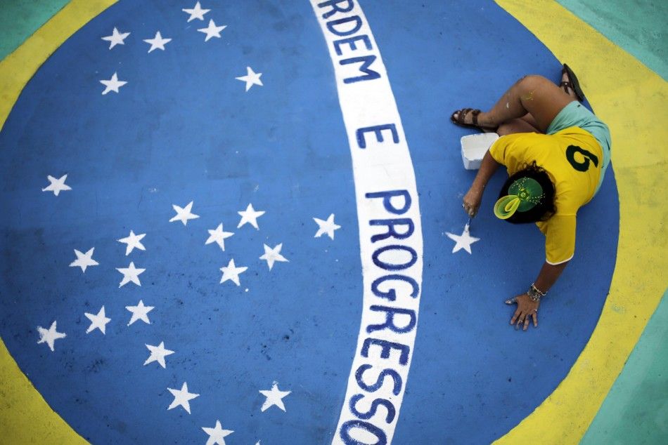 A woman paints the Brazilian national flag on the street 