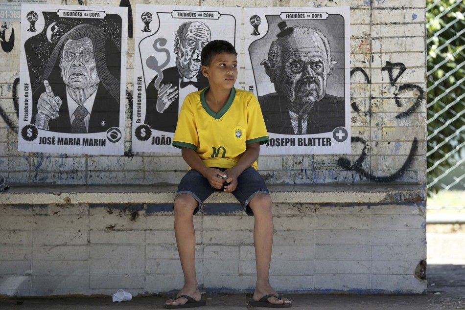 A boy sits on a bench in front of posters with caricatures 