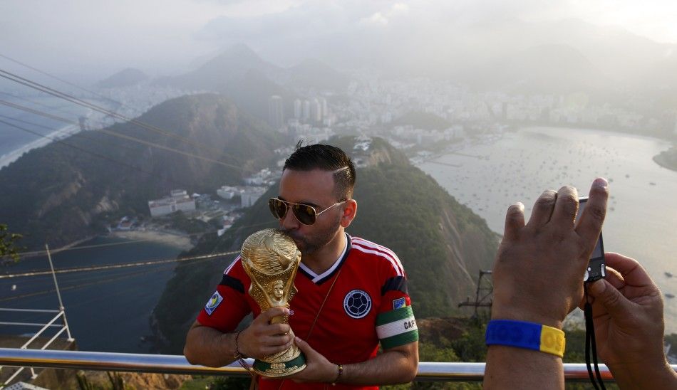 A supporter from Colombia has his picture taken with a replica of the World Cup 