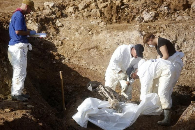 Forensic experts, members of the International Commision of Missing Persons (ICMP) and Bosnian workers search for human remains at a mass grave in the village of Tomasica near Prijedor, October 22, 2013. REUTERS/Dado Ruvic