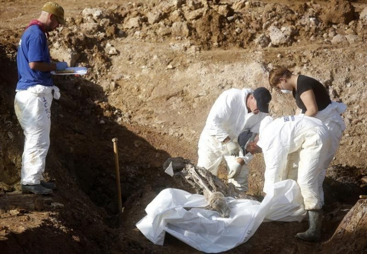 Forensic experts, members of the International Commision of Missing Persons (ICMP) and Bosnian workers search for human remains at a mass grave in the village of Tomasica near Prijedor, October 22, 2013. REUTERS/Dado Ruvic