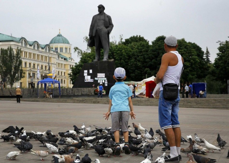 A father and his son enjoy a sunny day by a huge statue of Lenin in central Donetsk, May 28, 2014.