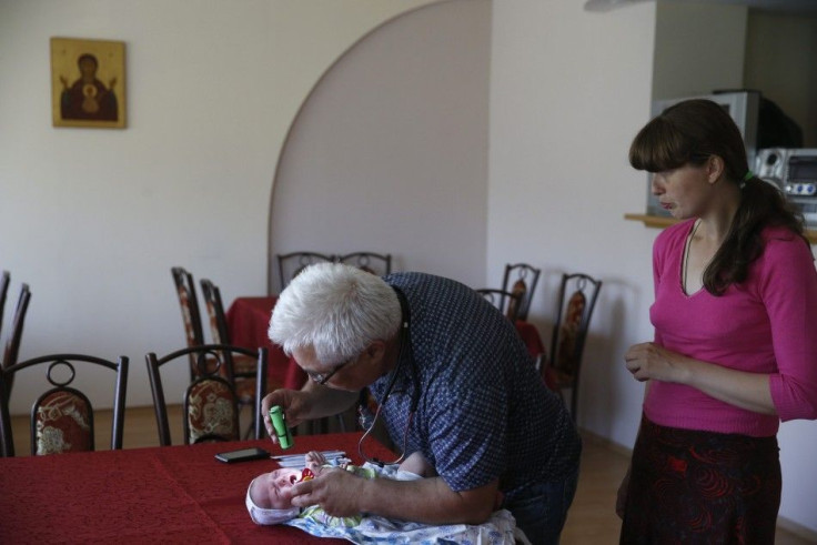 A doctor examines a baby whose family has fled fighting in Slaviansk, at the Makiyivsky Coke and Chemical Plant in the town of Makiyivka in eastern Ukraine June 4, 2014. Ukrainian government forces battled separatists with artillery and automatic weapons 