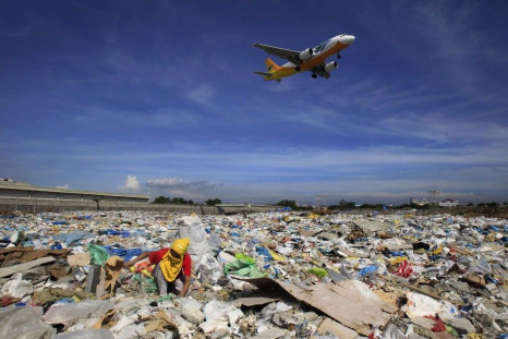 An aircraft flies overhead as a person rummages for recyclables at a garbage dumpsite in Paranaque city, metro Manila June 8, 2014. The United Nations declared &quot;Small Islands and Climate Change&quot; the theme of 2014 World Environment Day, with the 