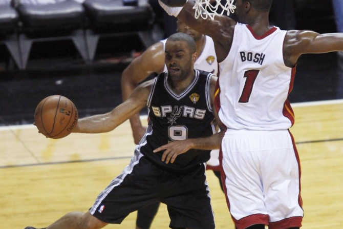 San Antonio Spurs' Tony Parker of France (L) dishes off past Miami Heat's Chris Bosh during the first quarter in Game 4 of their NBA Finals basketball series in Miami, Florida, June 12, 2014. 