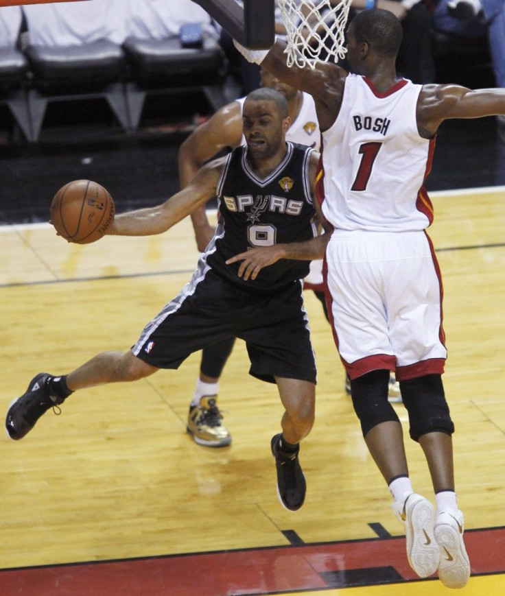 San Antonio Spurs' Tony Parker of France (L) dishes off past Miami Heat's Chris Bosh during the first quarter in Game 4 of their NBA Finals basketball series in Miami, Florida, June 12, 2014. 