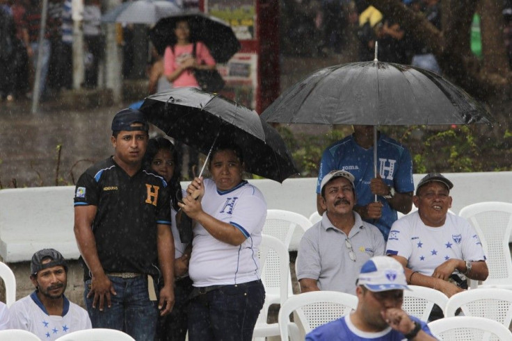 Honduran fans use umbrellas to take cover from rain as they watch the 2014 World Cup soccer match against France broadcasted on a large screen in downtown Tegucigalpa June 15, 2014. REUTERS/Jorge Cabrera (HONDURAS - Tags: SPORT SOCCER WORLD CUP SOCIETY)