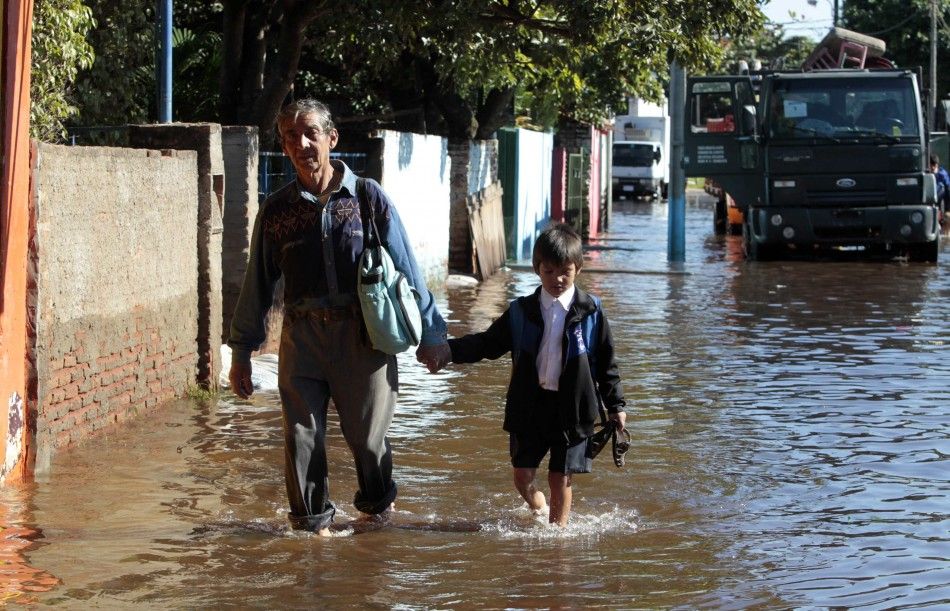 A man and his grandson walks through floodwaters near the Paraguay river in Asuncion, June 9, 2014. The National Emergency Secretary estimates that about 20,000 families are affected by the flooding of the countrys two main rivers, the Paraguay and the P