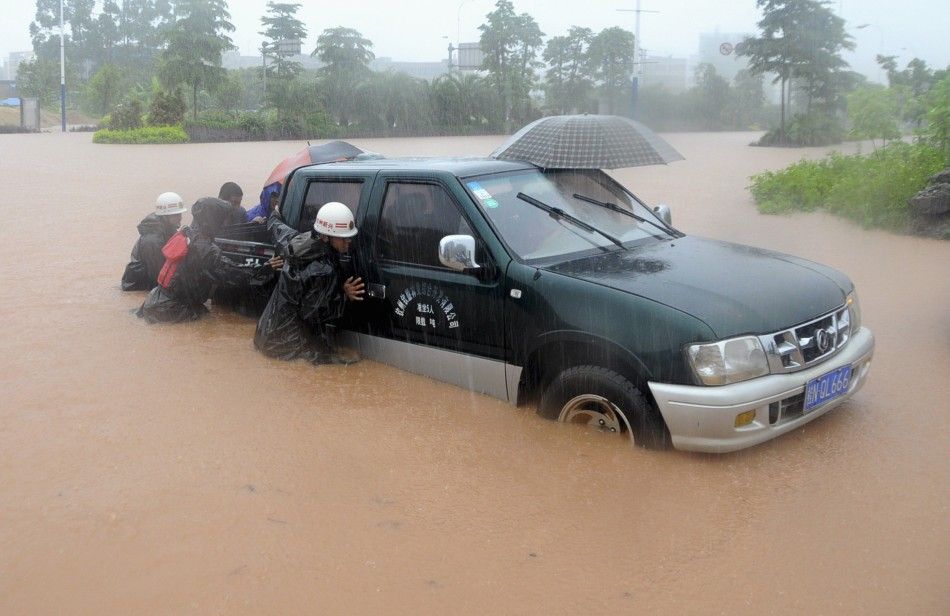 Rescue workers push a vehicle on a flooded street in Qinzhou, Guangxi Zhuang Autonomous Region, June 11, 2014. Torrential rain will continue to sweep south and southwest China over the next three days, the National Meteorological Center said on Monday, Xi