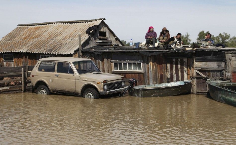 Local residents wait on the roof of houses surrounded by flood water in the settlement of Ust-Charish in Russias Altai region June 3, 2014. At least six died and up to 10,000 people lost their houses in Altai, where heavy floods had destroyed 230 kilomet