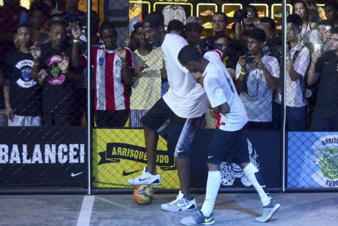 Basketball player Kobe Bryant of the U.S. (L) plays soccer with a Brazilian youth during a promotional event in Rio de Janeiro, June 14, 2014. Picture taken June 14, 2014.