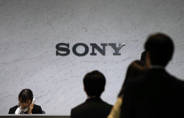 A Receptionist Speaks On A Phone Under A Sony Corp Logo.