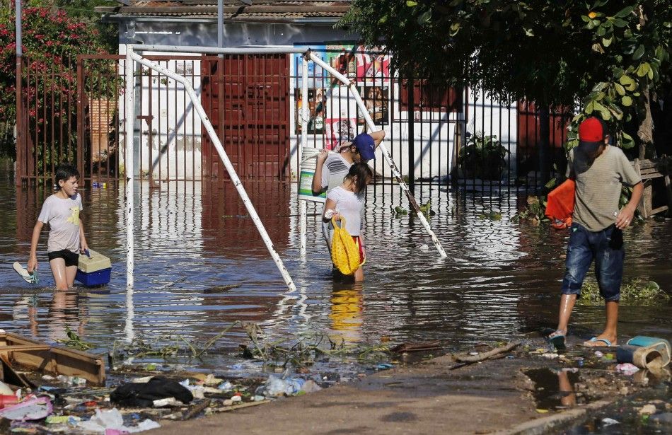 People walk through a flooded soccer field near the Paraguay river in Asuncion, June 9, 2014. The National Emergency Secretary estimates that about 20,000 families are affected by the flooding of the countrys two main rivers, the Paraguay and the Parana.