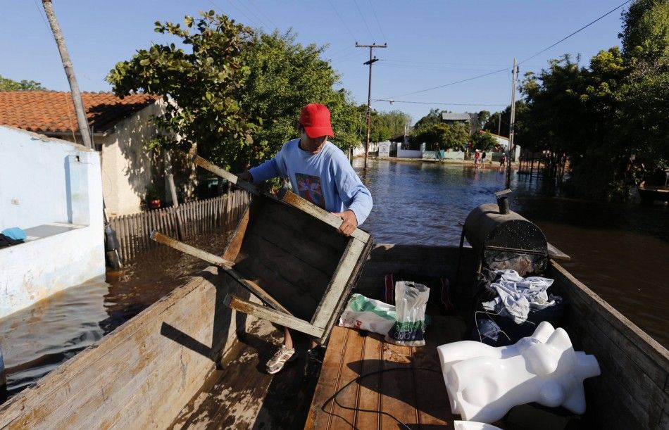 A man loads a table to the back of a truck as he removes his belongings from his flooded house near the Paraguay river in Asuncion, June 9, 2014. The National Emergency Secretary estimates that about 20,000 families are affected by the flooding of the cou