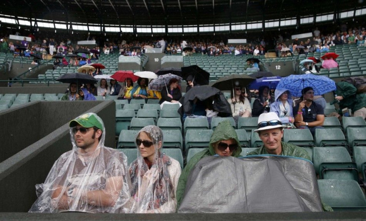 Spectators take cover from the rain on Court One at the Wimbledon Tennis Championships, in London June 30, 2014. REUTERS/Suzanne Plunkett (BRITAIN - Tags: SPORT TENNIS)