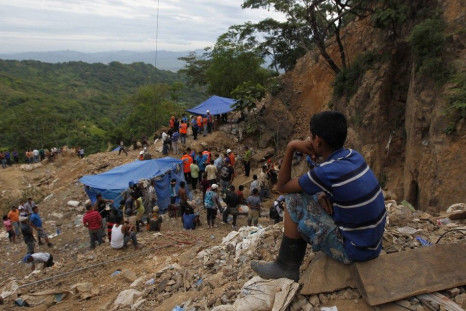 A child sits as he looks at miners and rescue workers the site of a landslide at a gold mine in San Juan Arriba, on the outskirts of Tegucigalpa July 3, 2014. Rescuers labored with pickaxes and shovels to dig out 11 miners trapped by a landslide at a smal
