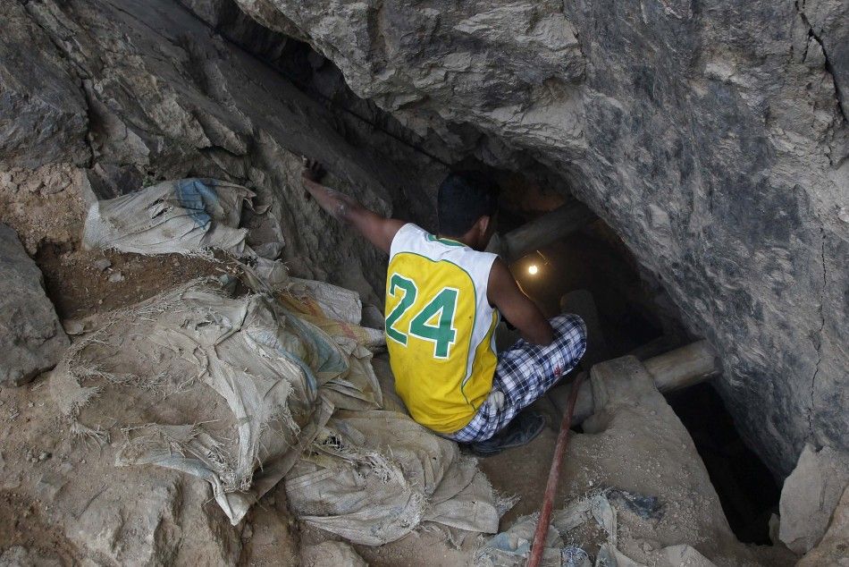 A miner holds a torch to illuminate the area through a crack on the floor at the site of a landslide at a gold mine in San Juan Arriba, on the outskirts of Tegucigalpa July 3, 2014. Rescuers labored with pickaxes and shovels to dig out 11 miners trapped b