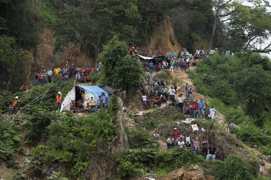 Miners and rescue workers stand at the site of a landslide at a gold mine in San Juan Arriba, on the outskirts of Tegucigalpa July 3, 2014. Rescuers labored with pickaxes and shovels to dig out 11 miners trapped by a landslide at a small gold mine in sout
