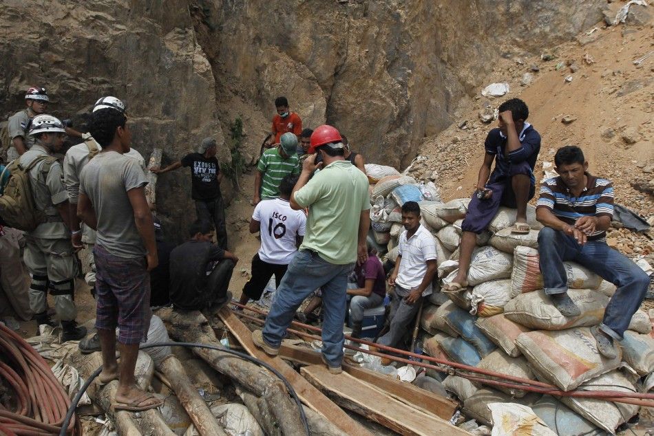 Miners and rescue workers stand at the entrance of a gold mine blocked by a landslide in San Juan Arriba, outskirts of Tegucigalpa July 3, 2014. Rescuers labored with pickaxes and shovels to dig out 11 miners trapped by a landslide at an illegal gold mine