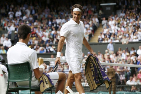 Roger Federer of Switzerland looks at Novak Djokovic of Serbia during a break in their men's singles finals tennis match on Centre Court at the Wimbledon Tennis Championships in London July 6, 2014. 