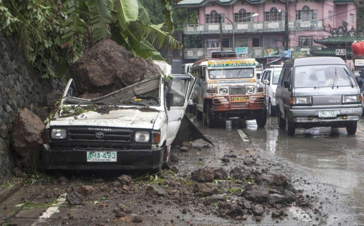 Motorists drive past a parked vehicle damaged by a landslide due to monsoon rains brought by Typhoon Ester in the mountain resort city of Baguio in northern Philippines June 10, 2014. Typhoon Ester, the first typhoon that hit Philippines after long summer