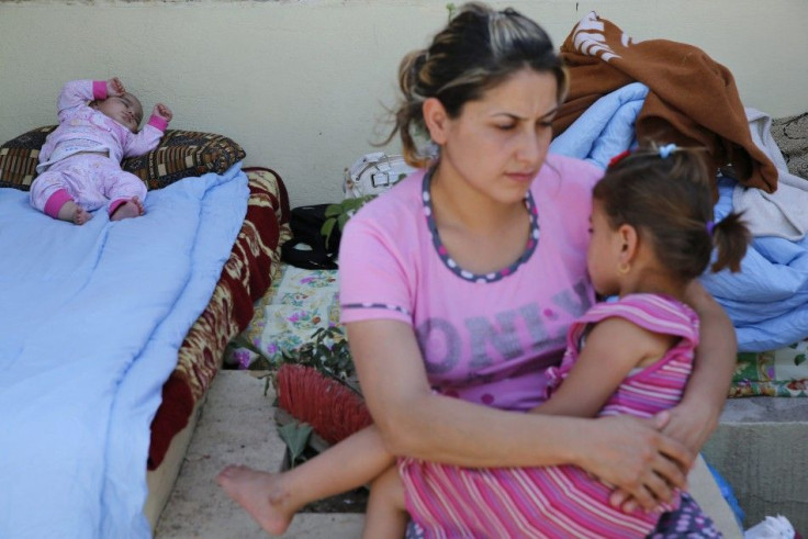 A Christian woman, who fled from the violence in Mosul two days ago, holds her daughter as her baby sleeps at a school in Arbil, in Iraq's Kurdistan region June 27, 2014. Iraqi forces launched an airborne assault on rebel-held Tikrit on Thursday with