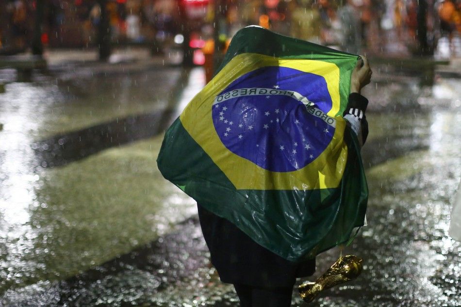 A Brazil soccer fan walks in the rain after watching a broadcast of their teams loss against Germany in their 2014 World Cup semi-final match in Rio de Janeiro