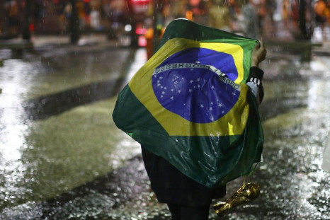 A Brazil soccer fan walks in the rain after watching a broadcast of their team's loss against Germany in their 2014 World Cup semi-final match in Rio de Janeiro