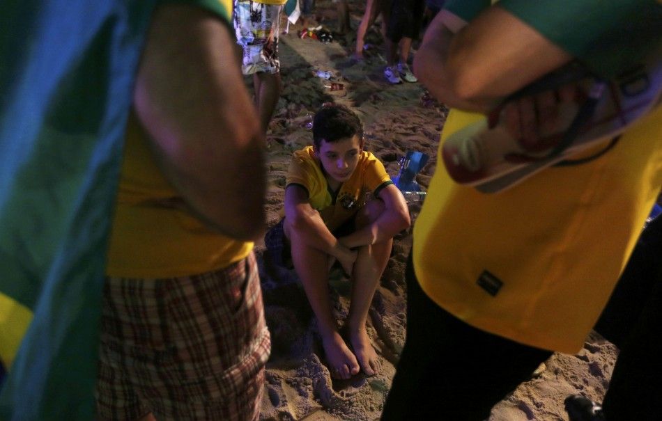 A Brazil fan sits dejected on the beach after the 2014 World Cup semi-final between Brazil and Germany at Copacabana beach in Rio de Janeiro