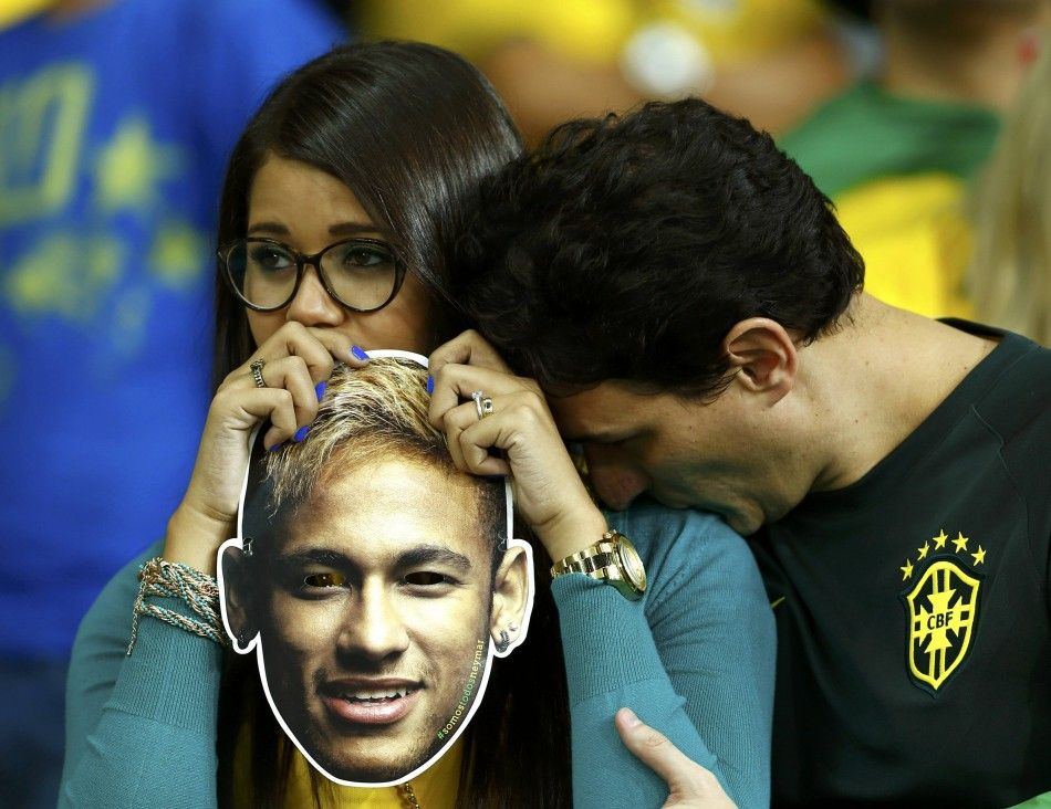 Brazil fans react while holding a mask of Neymar after the 2014 World Cup semi-finals between Brazil and Germany at the Mineirao stadium
