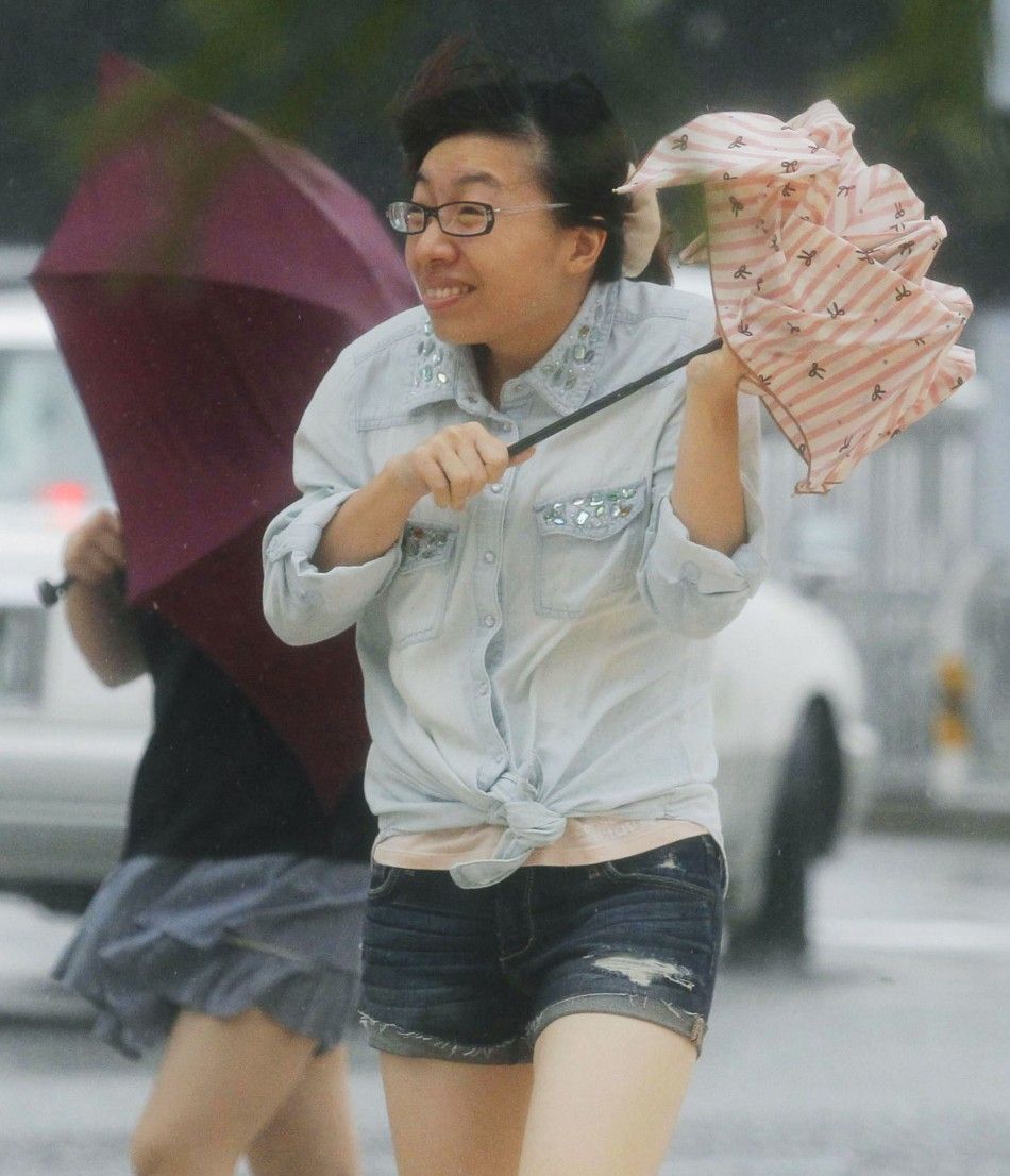 A woman holding an umbrella walks against strong winds and heavy rain brought about by Typhoon Neoguri on a street in Naha, on Japans southern island of Okinawa, in this photo taken by Kyodo July 8, 2014. One man died, more than 500,000 people were urged