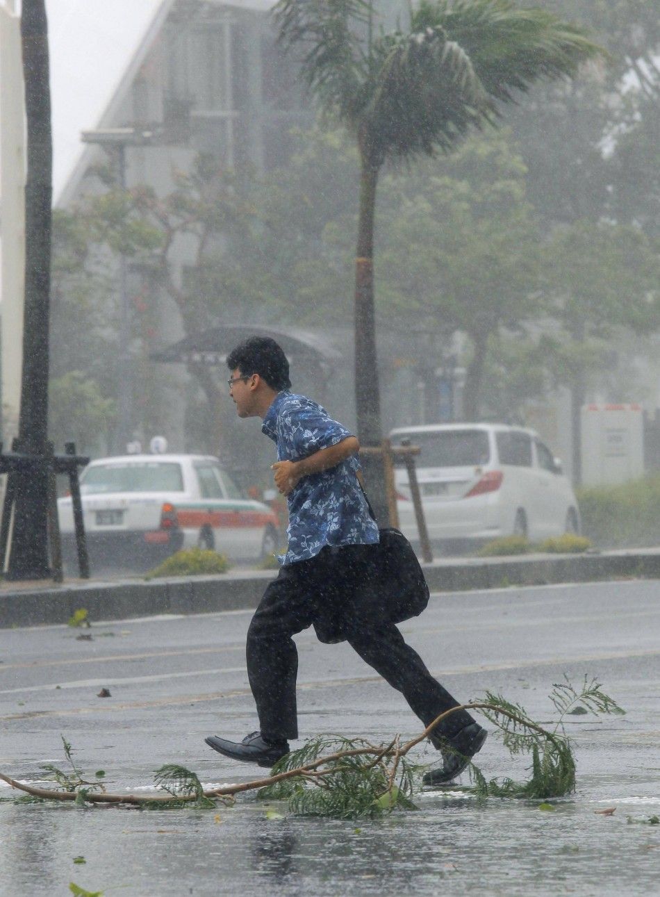 A man walks across a road at a pedestrian crossing amidst strong winds caused by Typhoon Neoguri in Naha, on Japans southern island of Okinawa, in this photo taken by Kyodo July 8, 2014. Hundreds of flights were cancelled in Japan and more than 500,000 p