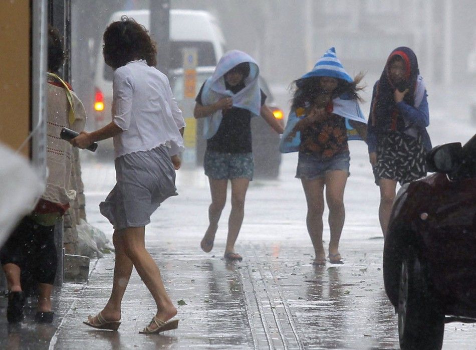 Women walk in strong winds caused by typhoon Neoguri at Kokusai street, a shopping and amusement district in Naha, on Japans southern island of Okinawa, in this photo taken by Kyodo July 8, 2014.  REUTERSKyodo