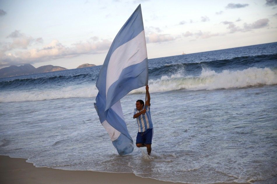 An Argentina fan runs with the countrys flag at Copacabana beach during a broadcast of the 2014 World Cup semi-final match against the Netherlands in Rio de Janeiro
