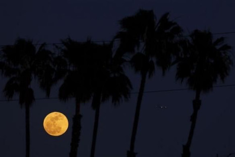 The full &quot;Super Moon&quot;, scientifically known as a &quot;perigee moon&quot;, rises under palm trees as an airplane lands at Los Angeles International Airport in Inglewood, California May 5, 2012.