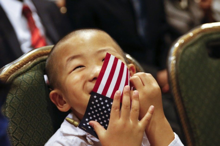 A child puts a flag over his face during a naturalization ceremony for one of his family members in New York