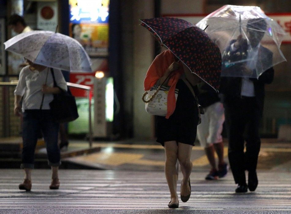People holding umbrellas cross a street in Tokyo during rain and winds caused by tropical storm Neoguri as the storm approaches Tokyo, July 10, 2014. Heavy rain battered a wide swathe of Japan on Thursday, sending rivers over their banks and setting off a