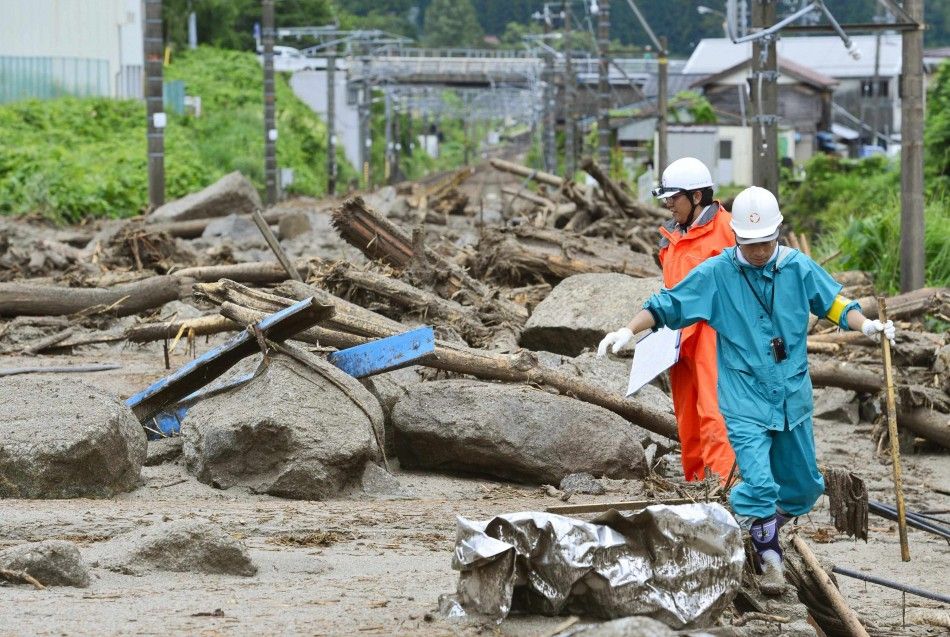 Workers walk among debris at an area affected by landslide caused by heavy rains due to Typhoon Neoguri in Nagiso town, Nagano prefecture, in this photo taken by Kyodo July 10, 2014. A landslide pummelled the town of Nagiso in central Japan late on Wednes
