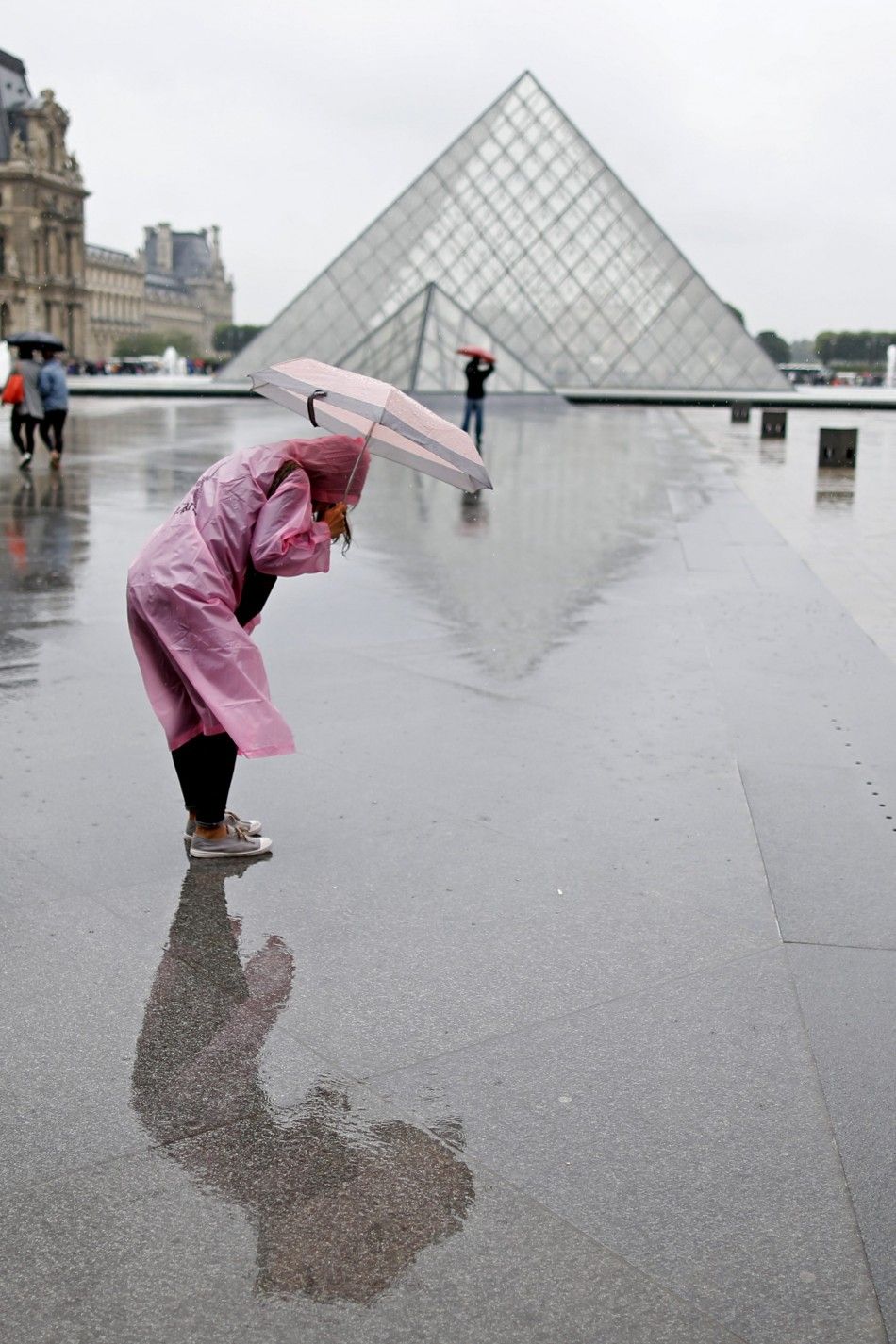 A tourist protects herself from the rain near the Pyramid of the Louvre Museum on a rainy summer day in Paris July 9, 2014.    REUTERSCharles Platiau FRANCE - Tags ENVIRONMENT TRAVEL