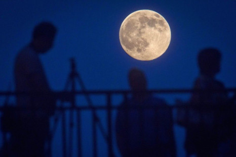 People stand and look at the moon one day ahead of the Supermoon phenomenon from a bridge over 42nd St. in the Manhattan borough of New York July 11, 2014. Occurring when a full moon or new moon coincides with the closest approach the moon makes to the Ea