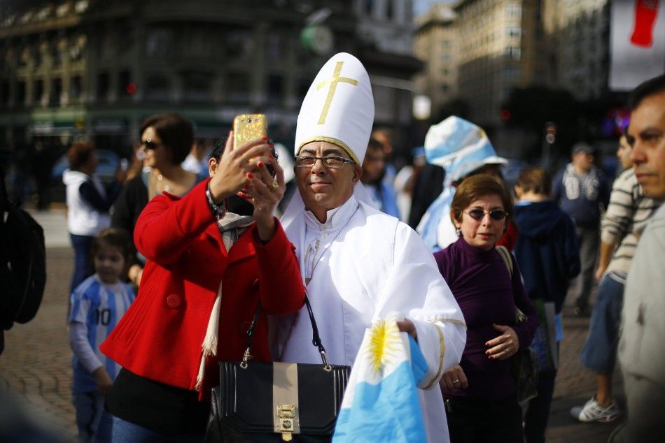 A soccer fan dressed up as Pope Francis holds Argentinas national flag while taking a selfie with a woman, before the teams World Cup final soccer match against Germany, in Buenos Aires July 13, 2014. REUTERSIvan Alvarado ARGENTINA - Tags SPORT SOCCE