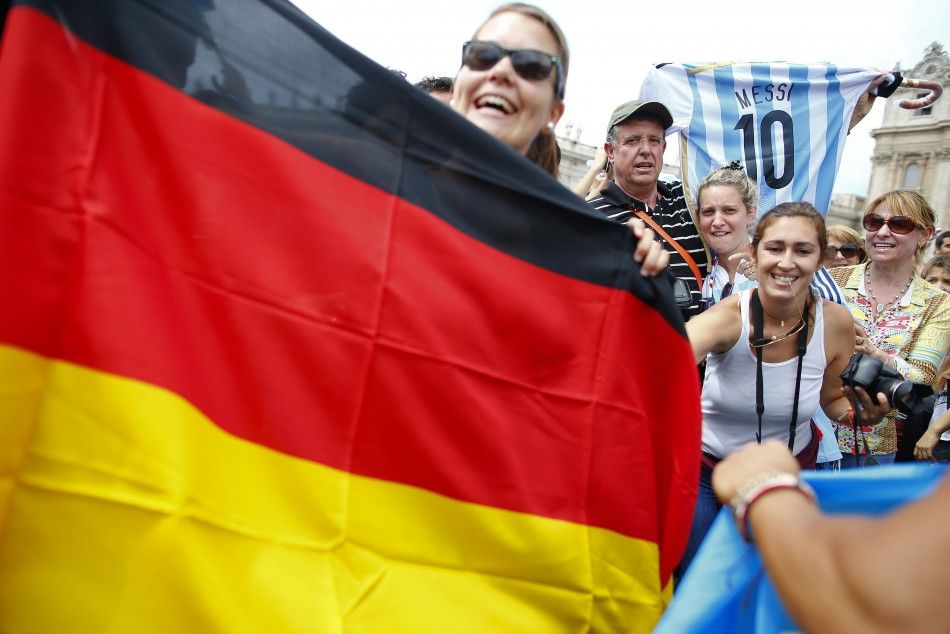 People holding a German flag and a soccer jersey with the number of Argentine national player Lionel Messi smile while waiting for Pope Francis Sunday Angelus prayer in Saint Peters square at the Vatican July 13, 2014. Three-times champions Germany take
