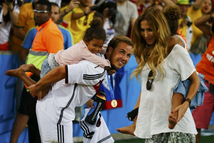Germany's Mario Goetze and his girlfriend Kathrin Brommel (R) carry the twin daughters of teammate Jerome Boateng, Soley and Lamia, at the end of during their 2014 World Cup final against Argentina at the Maracana stadium in Rio de Janeiro July 13, 2014. 