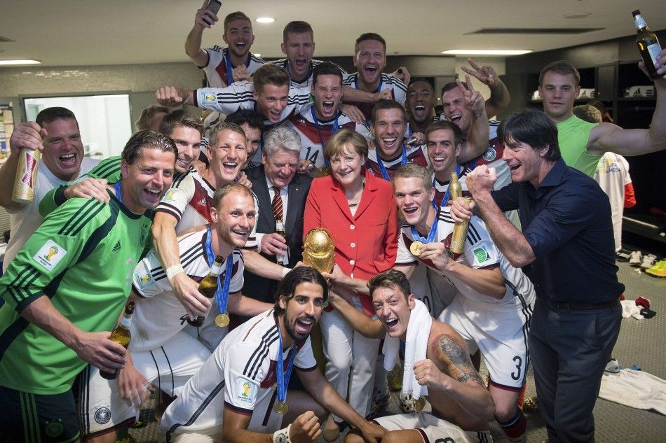 German Chancellor Angela Merkel centre R and German President Joachim Gauck centre L pose with the Germanys coach Joachim Loew front R and his players
