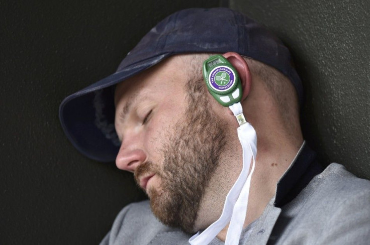 A spectator wearing headphones sleeps on Court Two at the Wimbledon Tennis Championships, in London