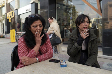 Pilates instructor Zainab Abbas smokes a cigarette as she sits with a friend after lunch in Lahore